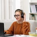 student-online-young-cute-girl-glasses-orange-sweater-studying-computer-with-headphones student-online-young-cute-girl-glasses-orange-sweater-studying-computer-with-headphones